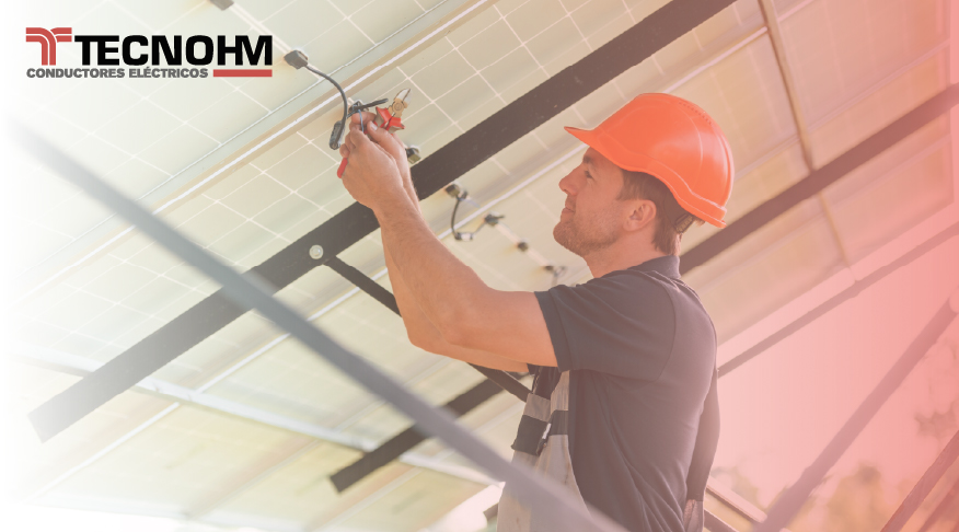 Técnico instalando cables solares homologados en estructura de paneles fotovoltaicos.